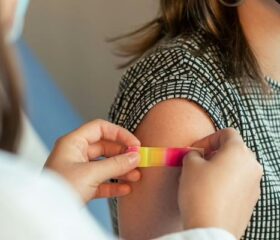 Pregnant woman getting a bandage placed over her flu shot injection site.