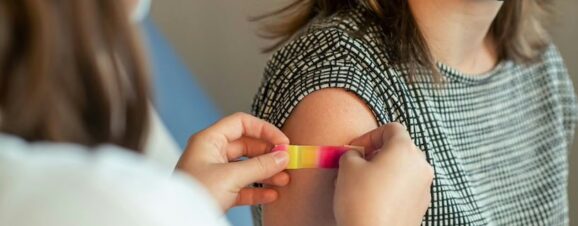 Pregnant woman getting a bandage placed over her flu shot injection site.