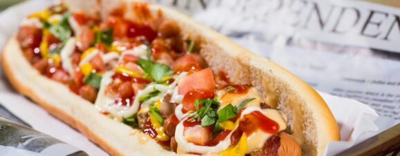 A hot dog in a bun slathered with condiments and toppings.