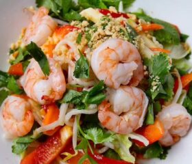 A plate of shrimp pasta with vegetables.
