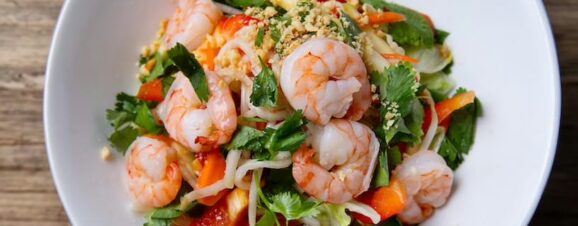 A plate of shrimp pasta with vegetables.