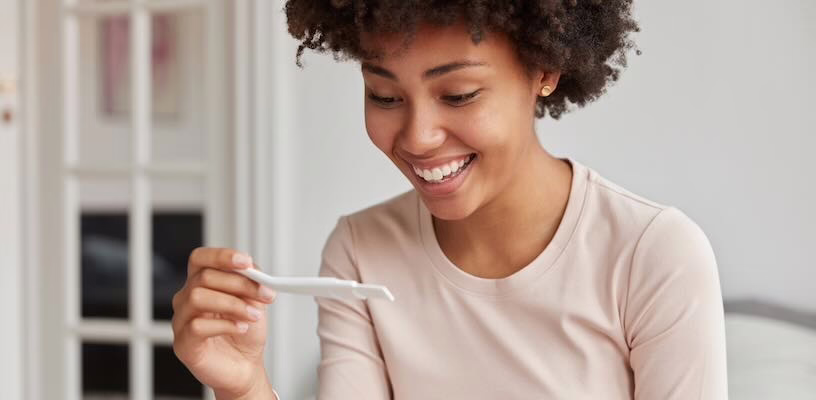 Woman with PCOS smiling down at a positive pregnancy test.