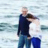 A man and a woman laughing while walking by the sea.