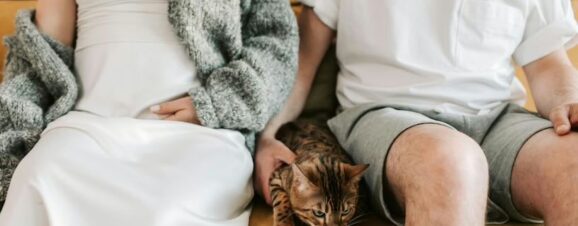Pregnant woman at risk of toxoplasmosis infection sitting next to cat.