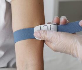 Woman having a strap placed on her arm in preparation for her non-invasive prenatal testing.