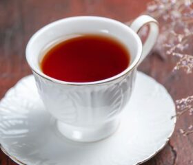 A full cup of red raspberry leaf tea sitting on a saucer.