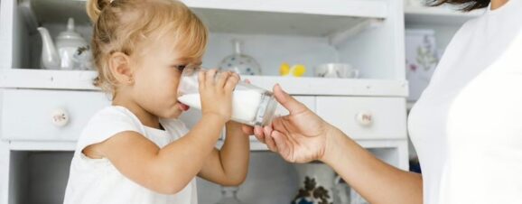 Toddler drinking a glass of cow's milk.