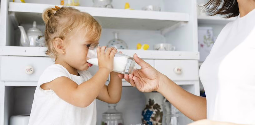 Toddler drinking a glass of cow's milk.