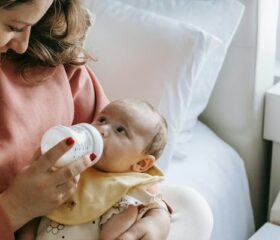 Woman overfeeding her baby, which will cause him to spit up.