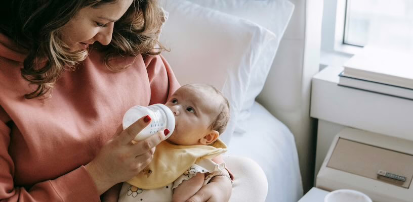 Woman overfeeding her baby, which will cause him to spit up.