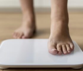 Close-up of a pregnant woman's feet as she steps onto a scale to track her weight gain.