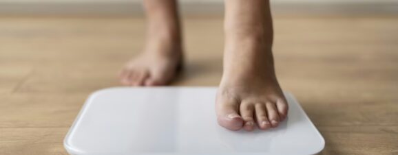 Close-up of a pregnant woman's feet as she steps onto a scale to track her weight gain.