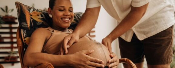A pregnant woman and her partner touching her bump to perform a kick count.