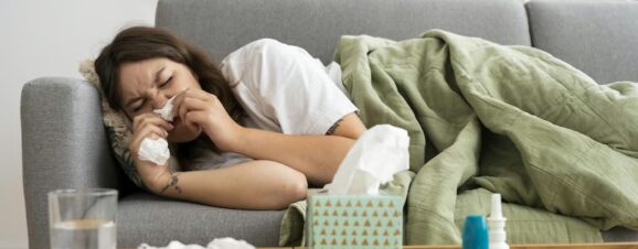 Congested pregnant woman lying on couch due to allergies.