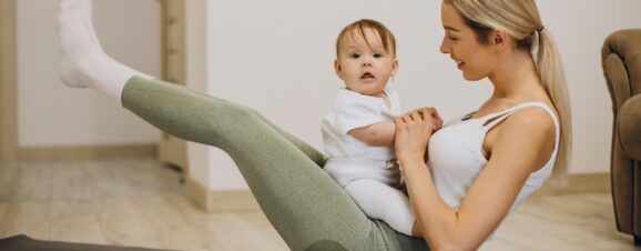 Mother holding her baby while working out as part of her postpartum weight loss plan.
