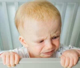 Baby crying in his crib as a result of separation anxiety.