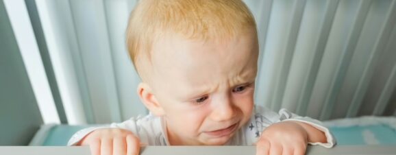 Baby crying in his crib as a result of separation anxiety.