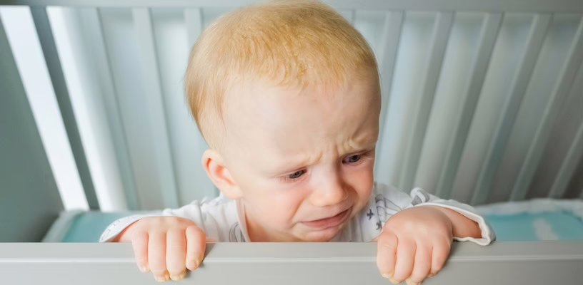 Baby crying in his crib as a result of separation anxiety.