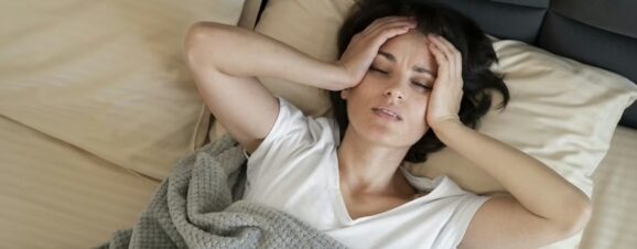 Woman with postpartum preeclampsia holding her head while struggling with a headache.