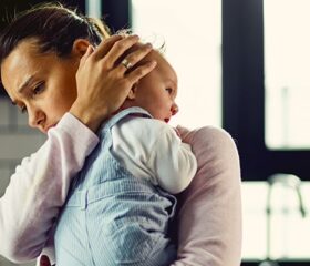 New mother experiencing the "baby blues" while holding her newborn.