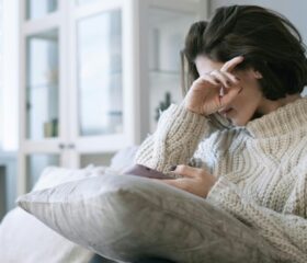 Woman holding her hand to her head and suffering from blurry vision during her pregnancy.