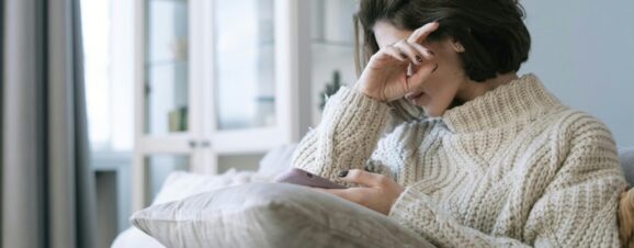 Woman holding her hand to her head and suffering from blurry vision during her pregnancy.