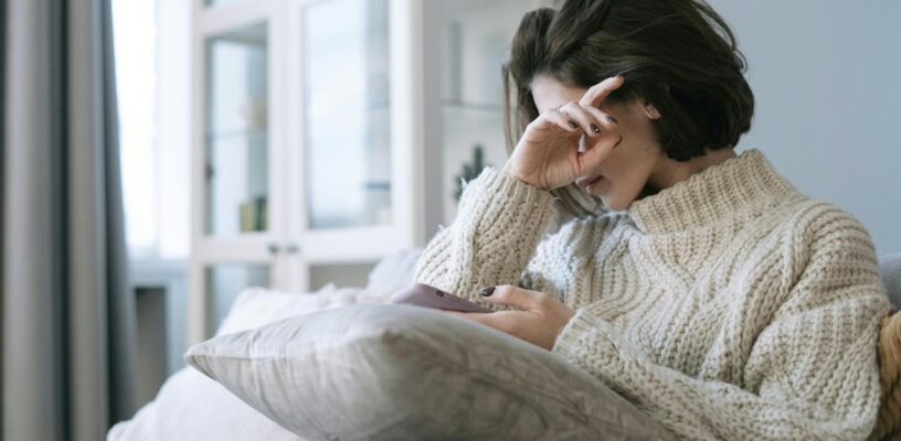 Woman holding her hand to her head and suffering from blurry vision during her pregnancy.