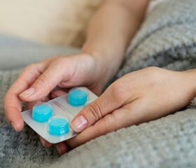 Pregnant woman opening pack of blue cough drops.