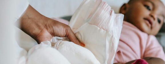 Mom putting a fresh diaper on her baby.