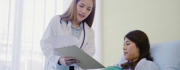 Doctor explaining an NT scan result to a pregnant woman lying in hospital bed.