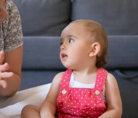 A mother sitting on the floor and telling her baby "no."